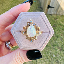 Load image into Gallery viewer, Gold ring with a large opal stone held in a hand against a grassy background