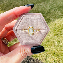 Load image into Gallery viewer, Hexagonal velvet ring box with a gold ring featuring a blue gemstone held by a hand.

