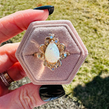Load image into Gallery viewer, Gold ring with a large opal stone held in a hand against a grassy background
