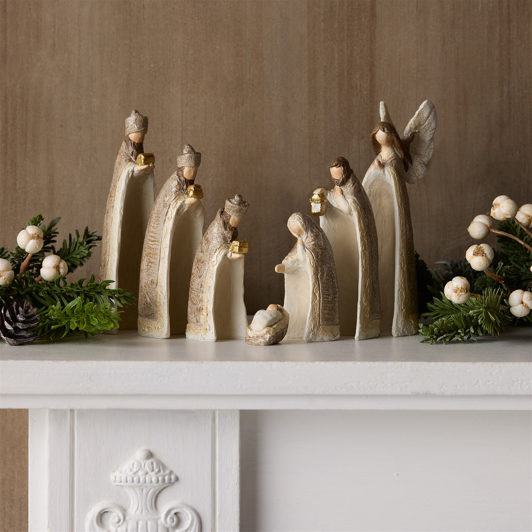 Decorative nativity scene with angel and shepherds on a mantelpiece.
