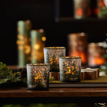 Load image into Gallery viewer, &quot;Frosted pine mercury glass votive holders glowing with warm candlelight&quot;
