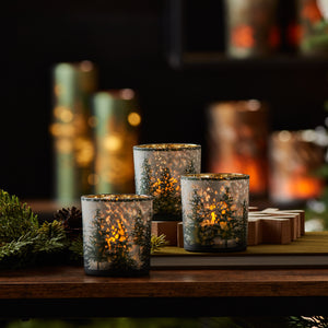 "Frosted pine mercury glass votive holders glowing with warm candlelight"