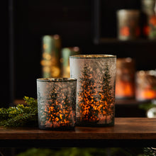 Load image into Gallery viewer, Close-up of frosted pine tree and snowflake design on mercury glass candle holder with candle glow
