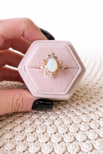 Load image into Gallery viewer, Pink hexagonal jewelry box with a gold ring featuring an opal stone on a textured surface.
