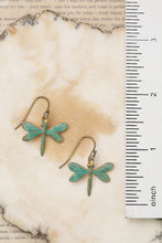Load image into Gallery viewer, Dragonfly-shaped earrings on a textured surface with a ruler for scale.
