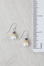 Load image into Gallery viewer, Pair of pearl earrings with gold accents on a textured surface next to a ruler.
