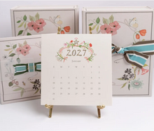 Load image into Gallery viewer, 2027 Karen Adams calendar displayed on gold easel
