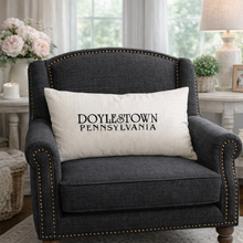 Load image into Gallery viewer, Gray armchair with a pillow displaying 'Doylestown Pennsylvania' in a cozy living room setting.
