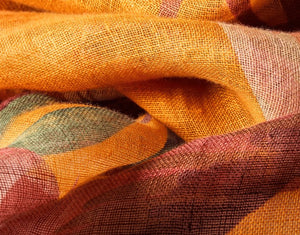 Close-up of ochre linen cotton scarf with detailed oriental crane print and soft woven texture